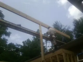 Carpenter setting a ridge beam over a new addition frame — Ice Dam Removal by Roofing Brothers in Italy