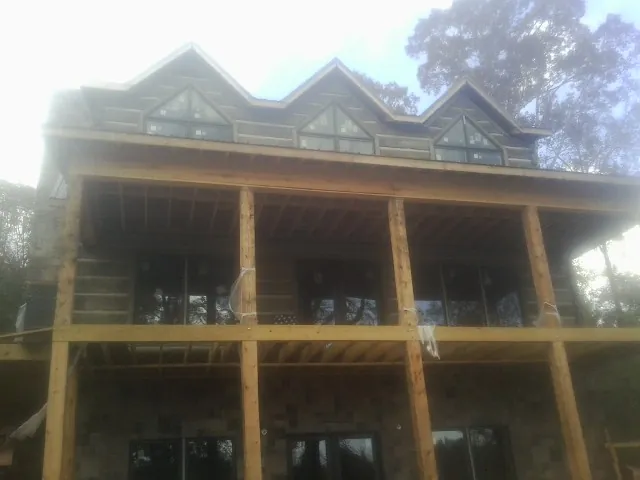 Dormers and porch framing on a large log home under construction — Roof Coating work by our crew in Italy