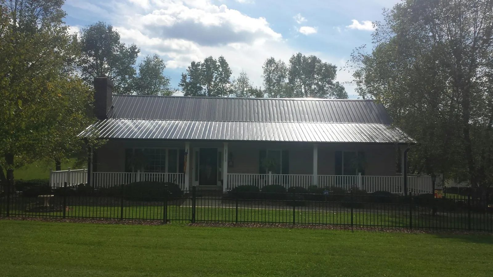 Gray metal roof on a brick ranch with a full width front porch — Gutter Guard Installation work by our crew in Italy