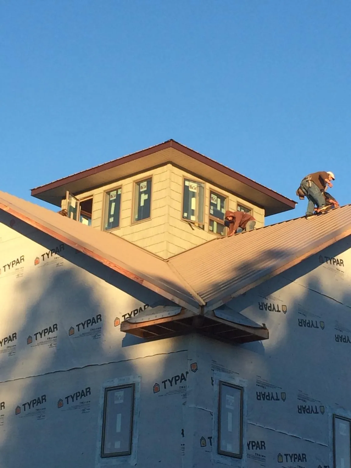 Roofers working around a rooftop cupola on a new metal roof at sunset — Roof Waterproofing in Italy by Roofing Brothers